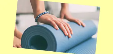 A person rolling an exercise mat on a yellow background.