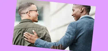 Two coworkers of different races smilling together on a purple background.