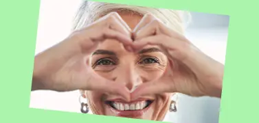 A woman with a hand gesture of love on a green background.