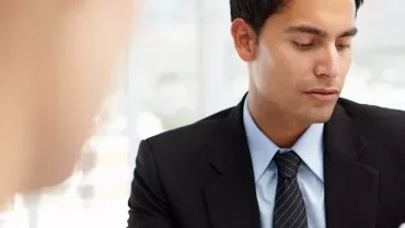 A person in a business suit reviewing papers.
