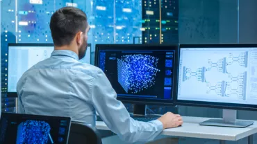 Persoon werkt op computerschermen met data en diagrammen.