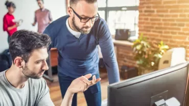 Two people collaborating at a computer in a modern office.