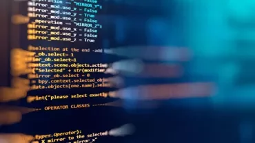 Close-up of computer code on a screen in a dark setting.