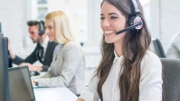 Customer service representatives working at desks with headsets.