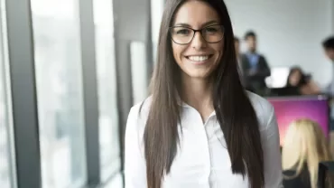 Person with glasses smiling in an office setting.