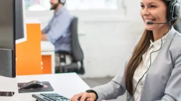 Persoon met headset werkt aan een computer in een kantoor.