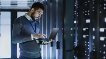 Person using a laptop in a server room