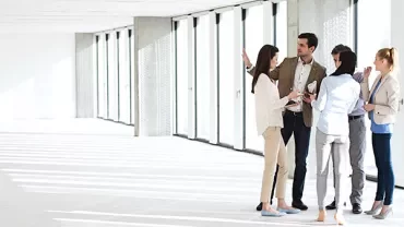 Group of people discussing in an empty room with large windows