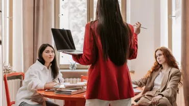 Drie personen in gesprek aan een vergadertafel.