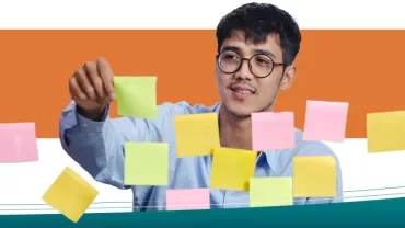 Persoon plaatst gekleurde sticky notes op glas.