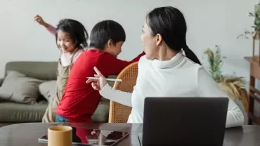 Vrouw kijkt naar kinderen die in de woonkamer spelen.