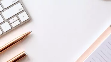Keyboard, pens, and notepads on a white surface.