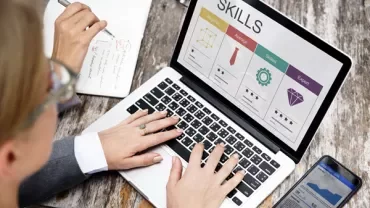 Person typing on a laptop showing a skills chart on the screen.