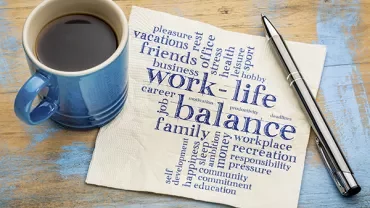 Coffee mug and napkin with work-life balance words.