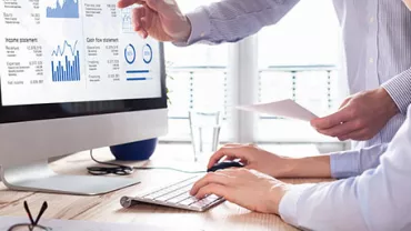 Mensen analyseren grafieken en financiële gegevens op een computerscherm.