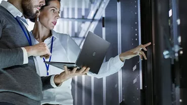 Twee mensen werken met laptop in serverruimte.