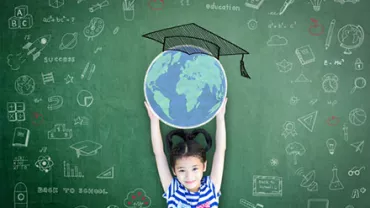 Child holds globe in front of chalkboard with educational drawings.