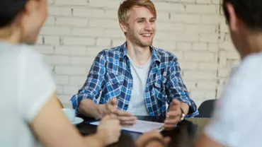 Three people having a conversation, one smiling at a table.