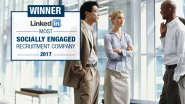 Three people having a professional conversation in a bright office.