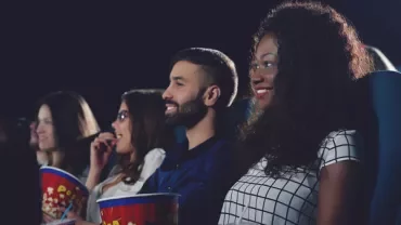 Group of people smiling while watching a movie in a theater.