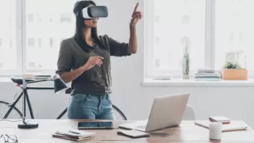 Person wearing VR headset in office with tech gadgets.