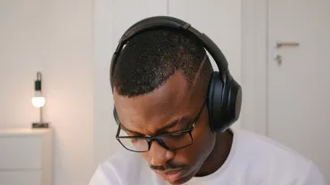 Person wearing headphones and glasses, concentrating.