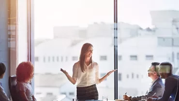 Person presenting in a modern conference room with a city view.