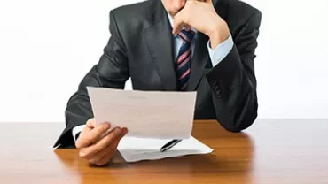 A person reading a document at a wooden table.