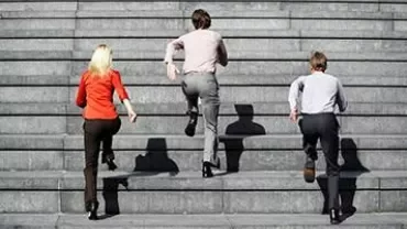 Three people running up a stone staircase.
