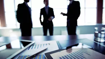 Group discussing in an office with charts on a table.