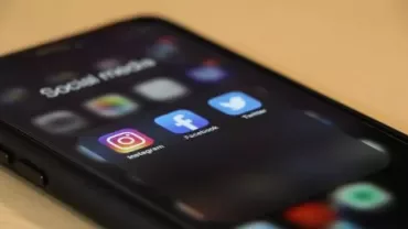 Smartphone displaying Instagram, Facebook, and Twitter icons on screen.