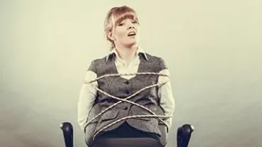 Person tied to a chair with rope, looking upwards.