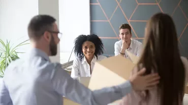 Groepsbijeenkomst in een kantoor, mensen om een tafel met een laptop.