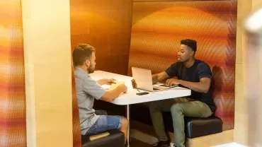Two people having a conversation in a cozy workspace.