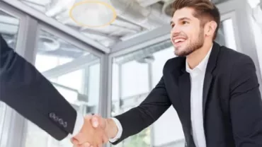 Person in suit shaking another person's hand in an office.