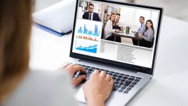 Laptop met videoconferentie en grafieken op het scherm.