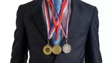 Person in a suit wearing three medals around the neck.