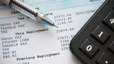 A pen and calculator on a payroll document.