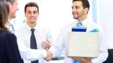 People shaking hands in an office setting, smiling.