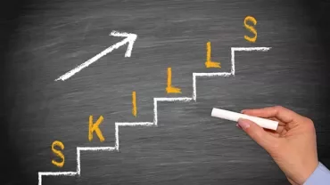 Chalk-drawn stairs on a blackboard spelling 'skills' with an arrow pointing upward.