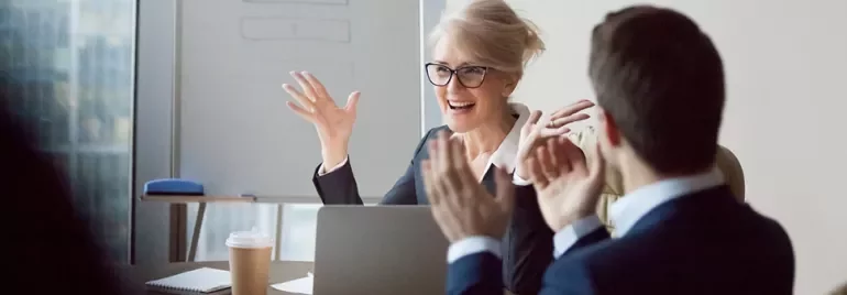 Two people clapping in a meeting room.