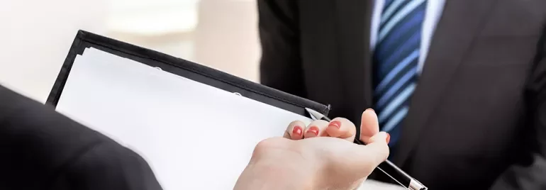 Hand with pen over blank paper, set for interview.