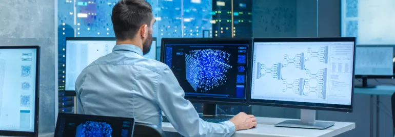 Persoon werkt op computerschermen met data en diagrammen.