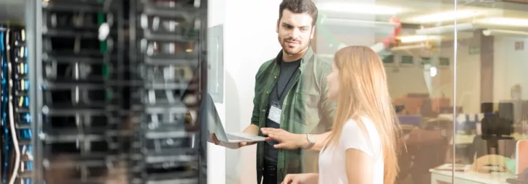 Mensen discussiëren en gebruiken een laptop in een serverruimte.