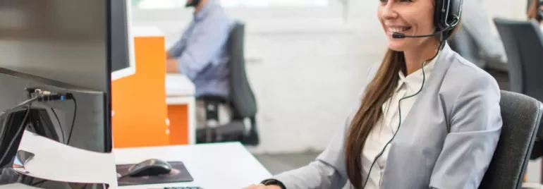 Persoon met headset werkt aan een computer in een kantoor.