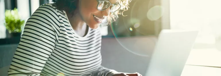 Persoon typt op een laptop met zonnebril en zonlicht flitsen.