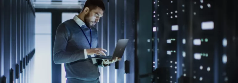 Persoon werkt op laptop in serverruimte