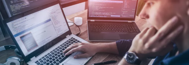 Persoon werkt aan computercode op laptops.