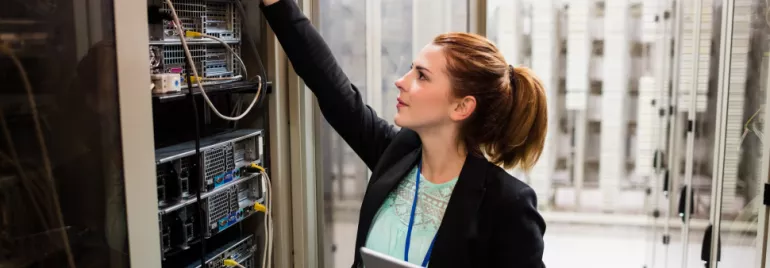 Person working in a server room, handling cables and equipment.