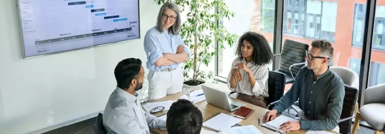 Groep collega’s in een vergaderruimte met een presentatie op het scherm.